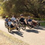 Vier mensen oefenen het rijden op ligfietsen op een zonnig pad