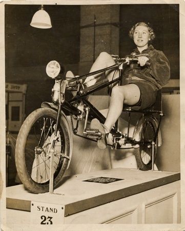Historische ligfiets met berijdster op een tentoonstelling, stand 23