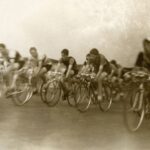 Historische wielrenners rijden dicht naast elkaar op racefietsen