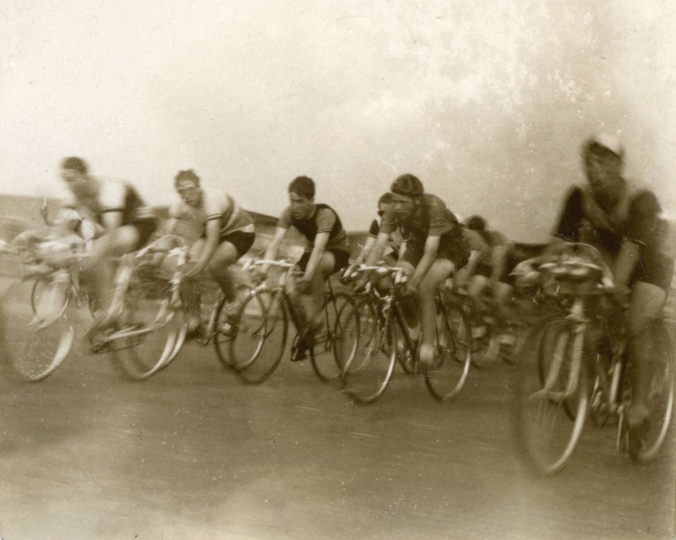 Historische wielrenners rijden dicht naast elkaar op racefietsen
